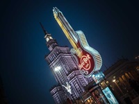 Neon-Gitarre vom Hard Rock Cafe mit dem Kulturpalast in Warschau bei Nacht