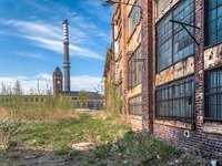 Altes Fabrikgebäude mit hohen Schornstein im Hintergrund